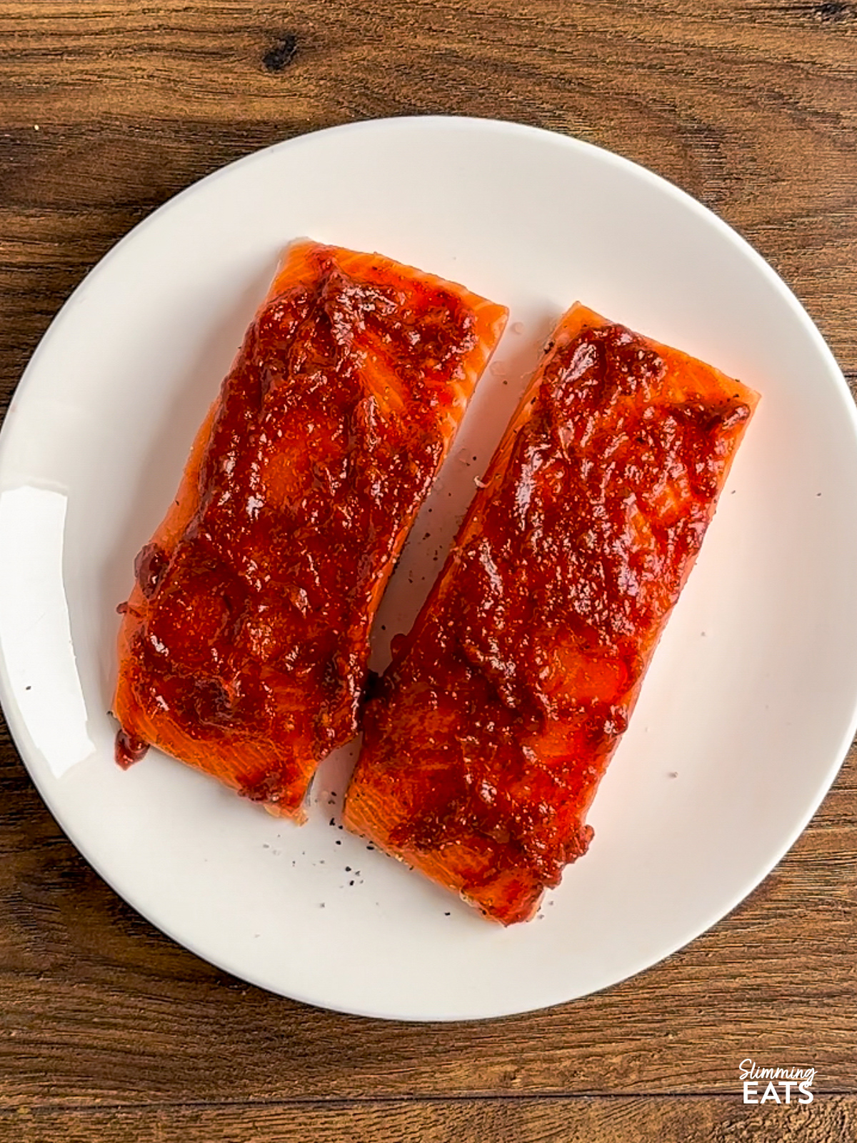salmon fillets on a white plate with honey harissa paste on top