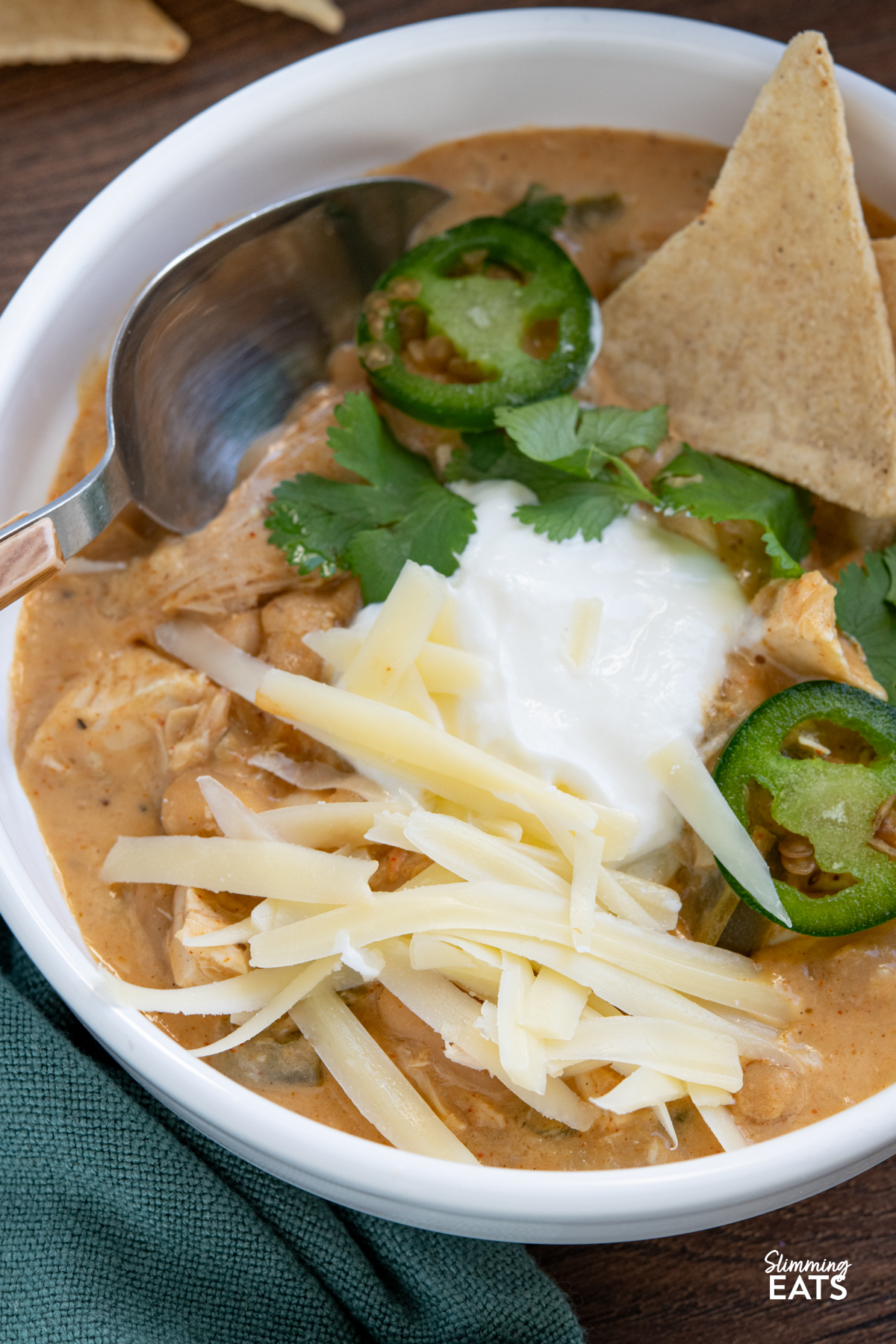 close up of White Chicken Chili in a white bowl with toppings