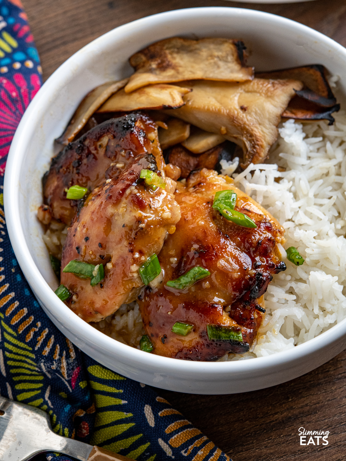 orange dijon chicken thighs in white bowl with king oyster mushrooms and rice