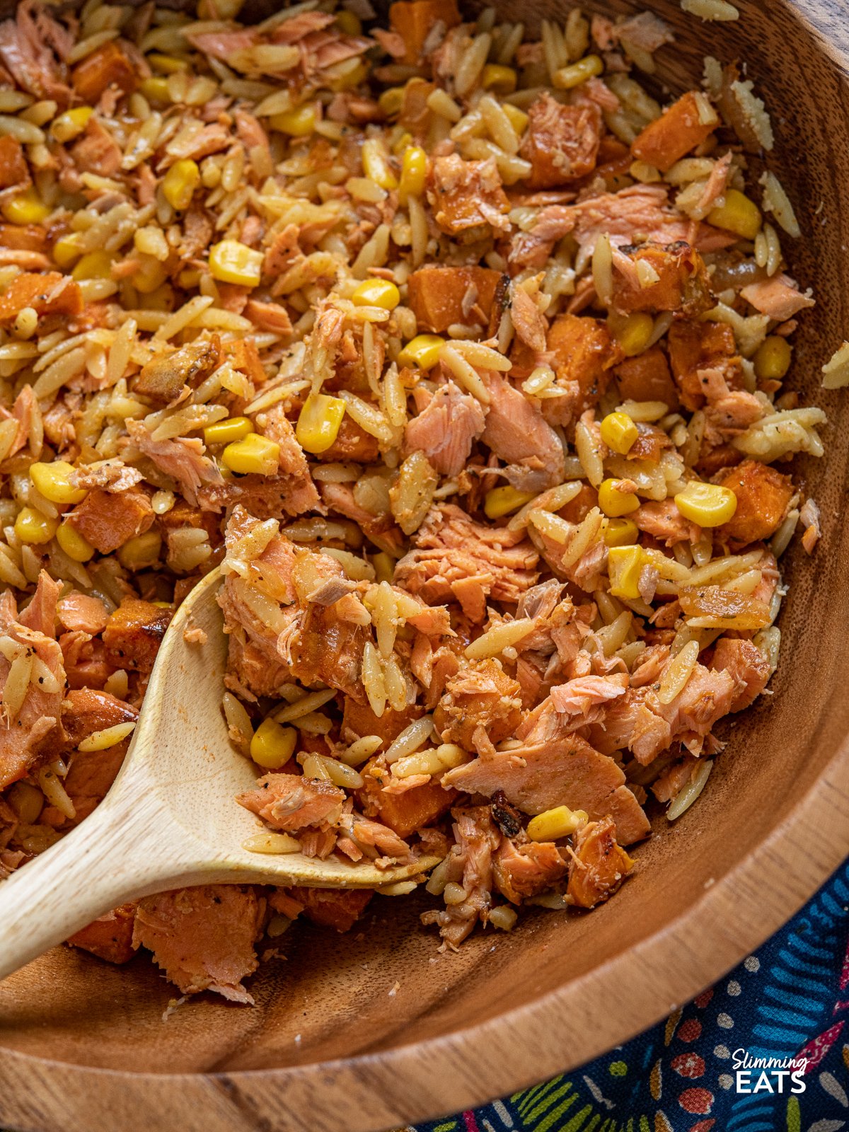 close up of Salmon, Sweet Potato, Corn and Orzo Salad in wooden bowl