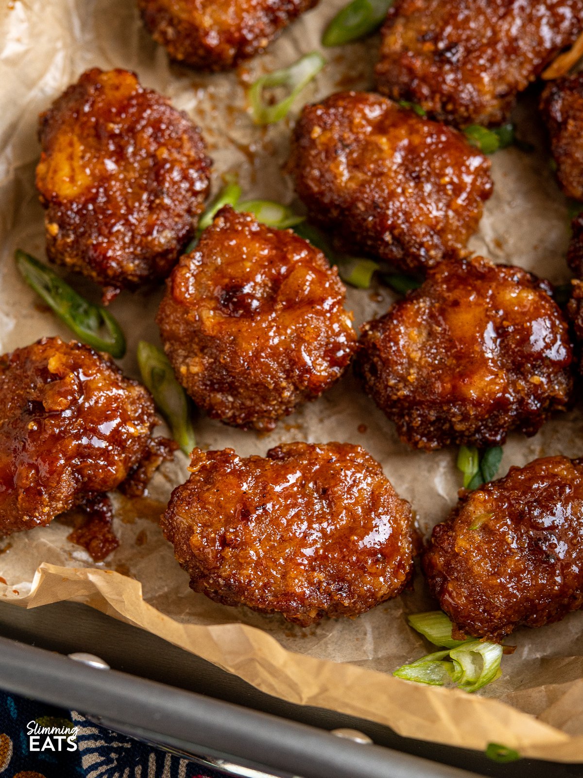 close up of Air Fryer Honey BBQ Chicken Nuggets on a baking tray with parchment paper