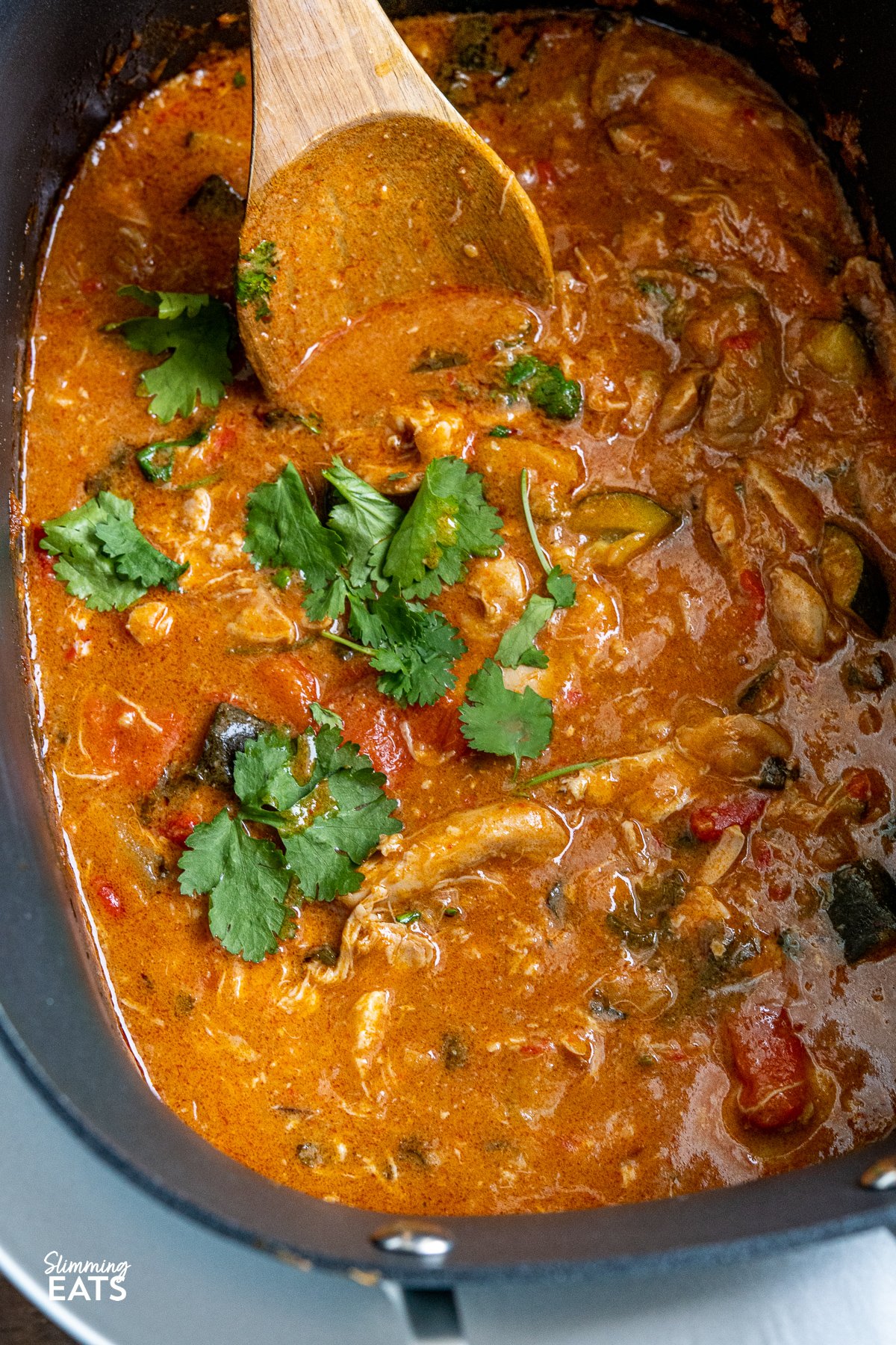Enjoy the delicious flavours of this Slow Cooker Thai Peanut Chicken Curry—a delightful family-friendly weeknight sensation made with tender chicken thighs, creamy coconut milk, fiery Thai red curry paste, and the richness of peanut butter. Slow Cooker Thai Peanut Chicken Curry in a slow cooker with wooden spoon