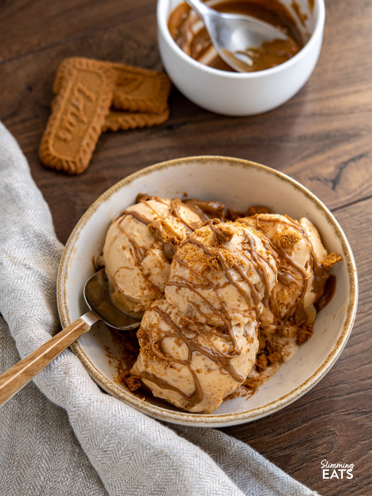 Homemade Biscoff Ice Cream in a cream bowl with biscoff drizzle and cookie crumb