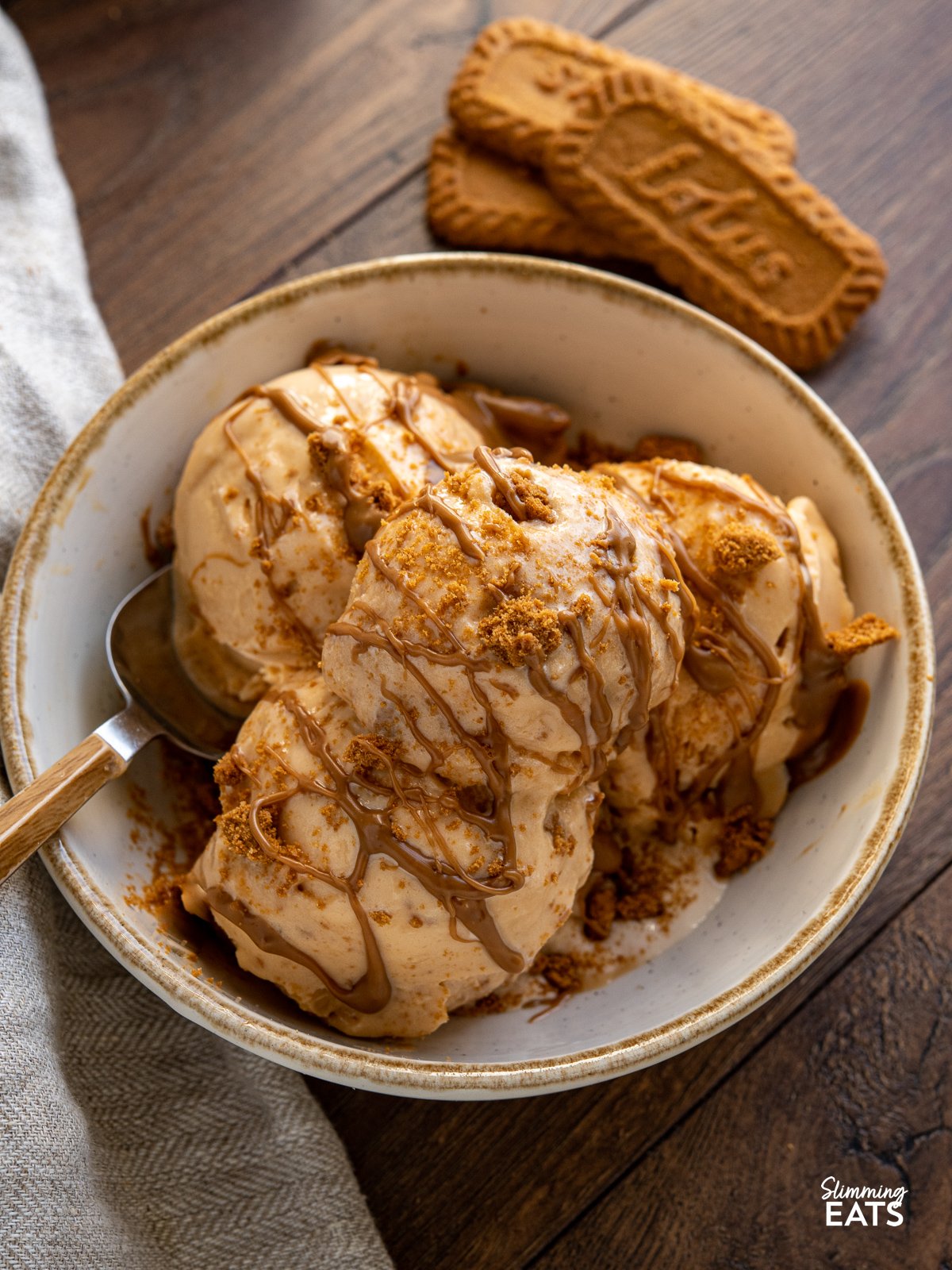 close up of Homemade Biscoff Ice Cream in a cream bowl with biscoff drizzle and cookie crumb. 