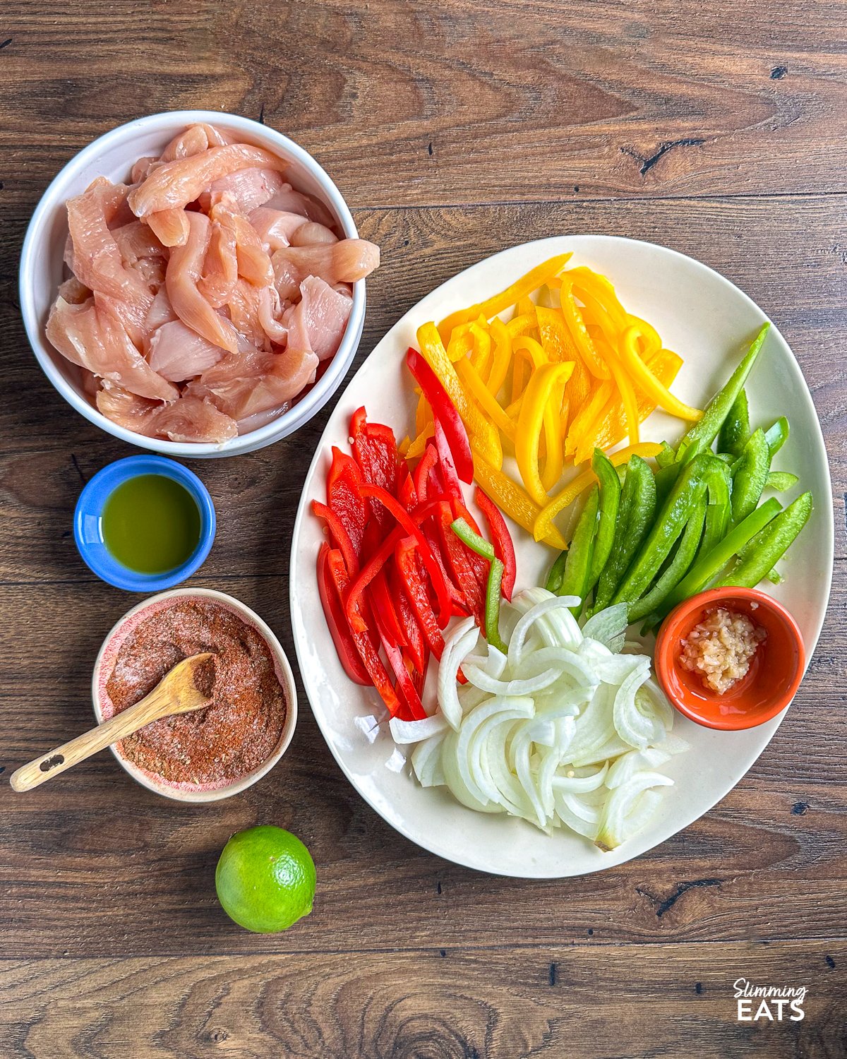 Are you looking for a quick and easy delicious dinner that is perfect for the whole family? Look no further than these simple Air Fryer Chicken Fajitas with tender chicken strips and mixed peppers and onion, all in the perfect homemade fajita seasoning blend. ingredients for Air Fryer Chicken Fajitas on a wooden board