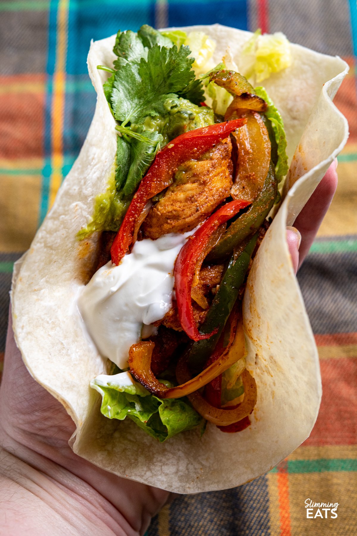 Air Fryer Chicken Fajitas in a soft tortilla with cilantro, guacamole, lettuce and soured cream