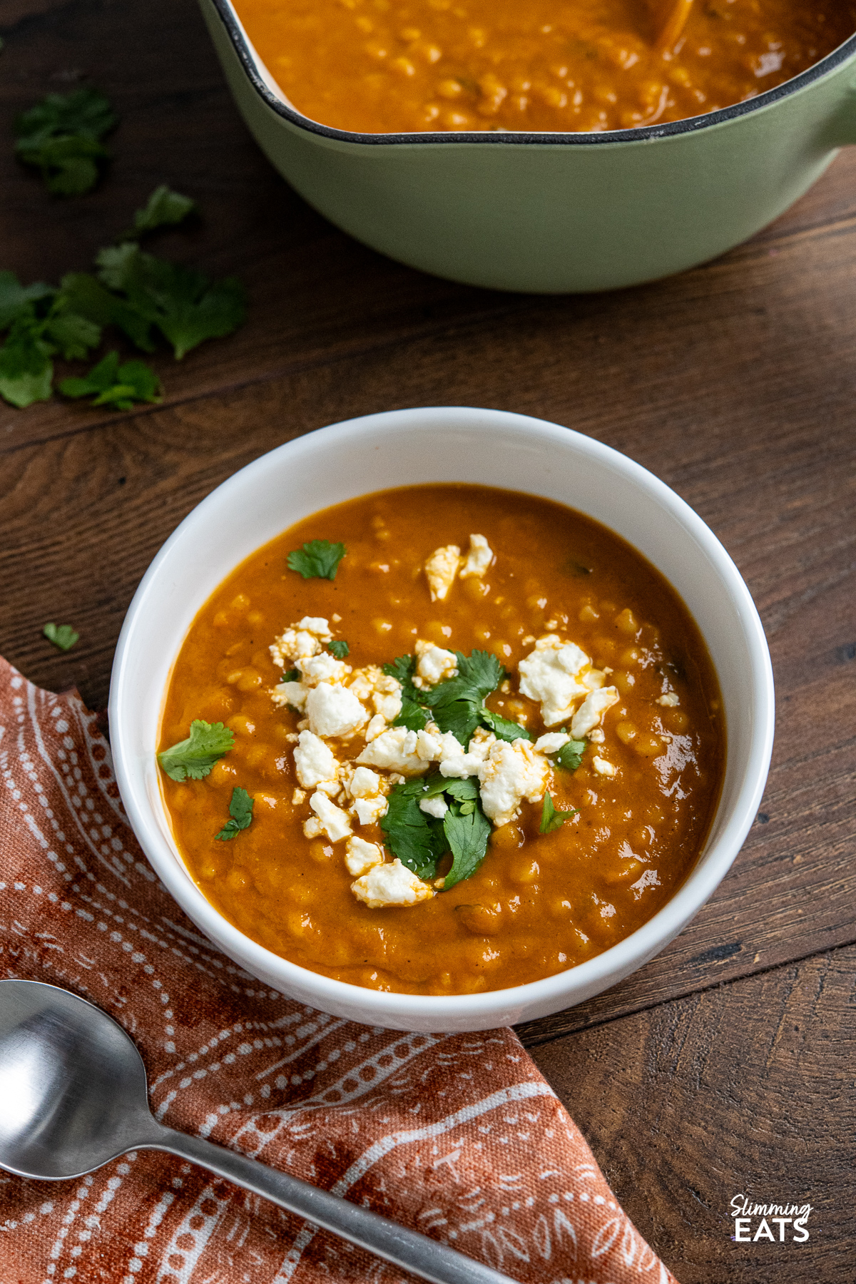 Roasted Vegetable Soup in white bowl with crumbled feta, israeli couscous and coriander.