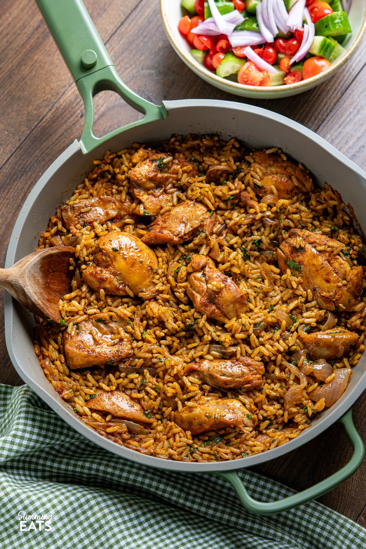 If you're in search of a hassle-free, one-pan recipe bursting with flavour, you're going to adore this One Pot Shawarma Chicken and Rice, featuring an exquisite blend of Middle Eastern spices. chicken shawarma and rice in a green ceramic non stick pan with a bowl of mixed salad