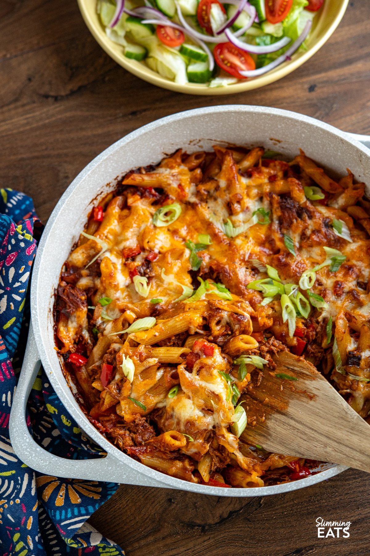 Pulled Pork Pasta Bake in ceramic double handled light grey pan with yellow bowl of salad above.