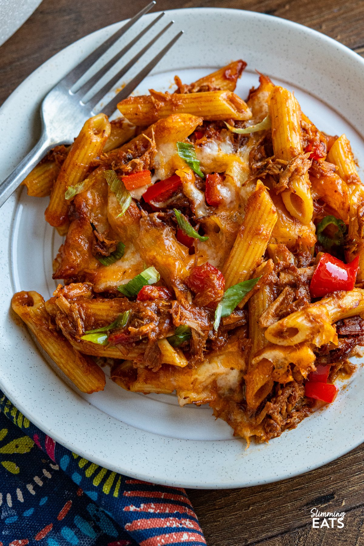 close up of serving of Pulled Pork Pasta Bake on beige and white plate with silver fork