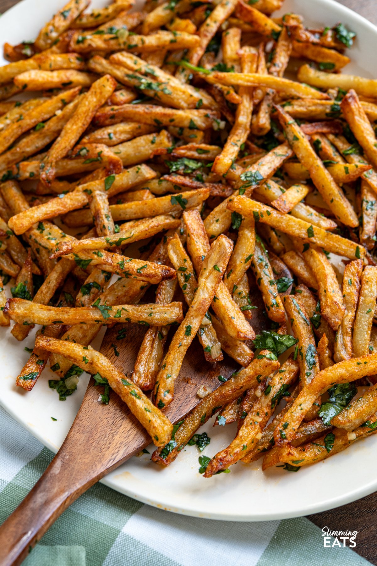 Savour the delicious fusion of these oven-baked seasoned fries, boasting a perfect crispiness, and the tantalizing harmony of garlic, butter, and cilantro. These delectable Garlic Cilantro Fries aren't just a side dish; they're a culinary revelation, ready to be relished either on their own with your preferred dip or as the star of any meal. close up of Garlic Cilantro Oven Baked Fries on oval plate