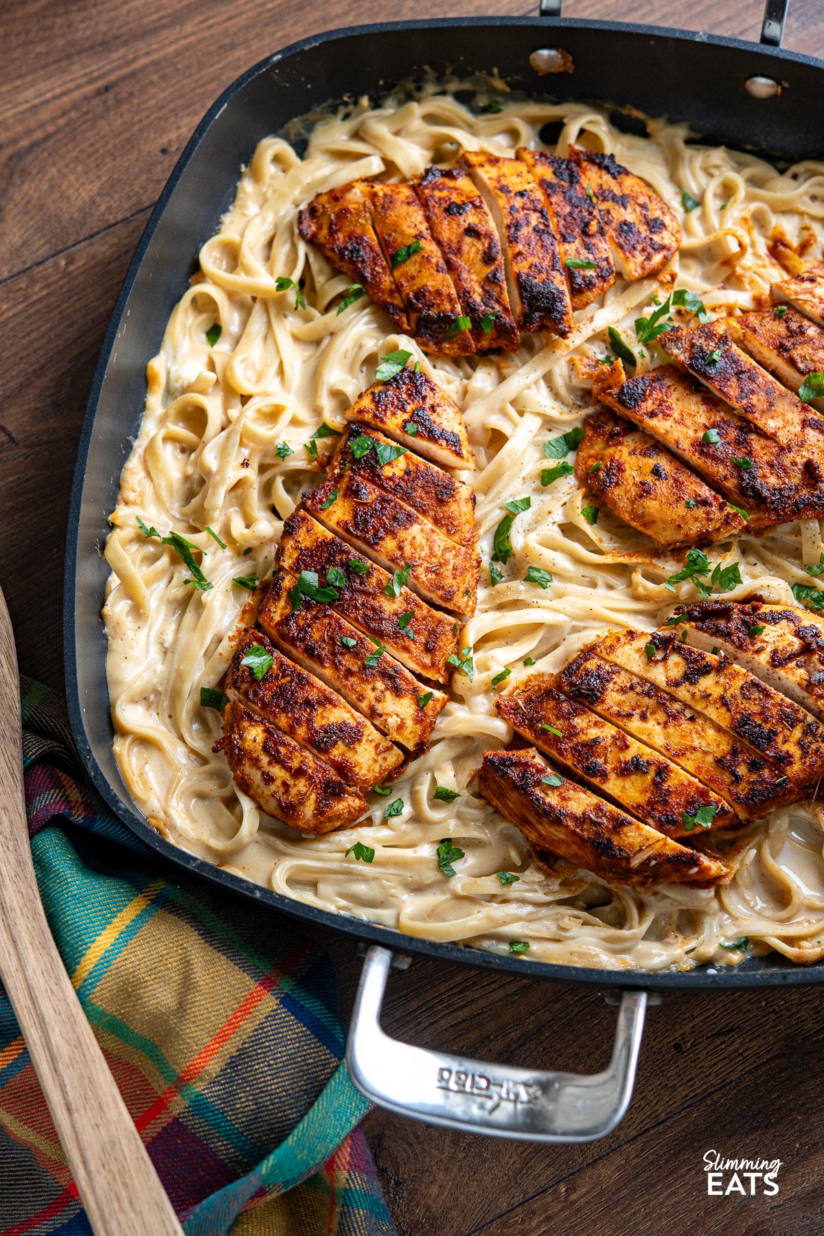 One Pot Cajun Chicken Alfredo - This mouthwatering dish features tender chicken breast seasoned to perfection with a homemade blend of bold Cajun spices, nestled into a lighter creamy Alfredo-coated fettuccine. close up of One Pot Cajun Chicken Alfredo Pasta in a square frying pan