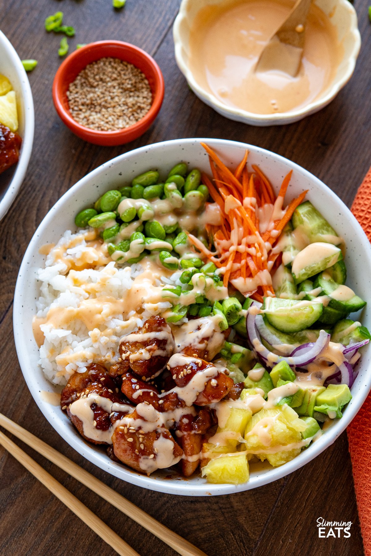 White bowl filled with Hawaiian chicken poke bowl topped with assorted fresh toppings drizzled with spicy mayo 