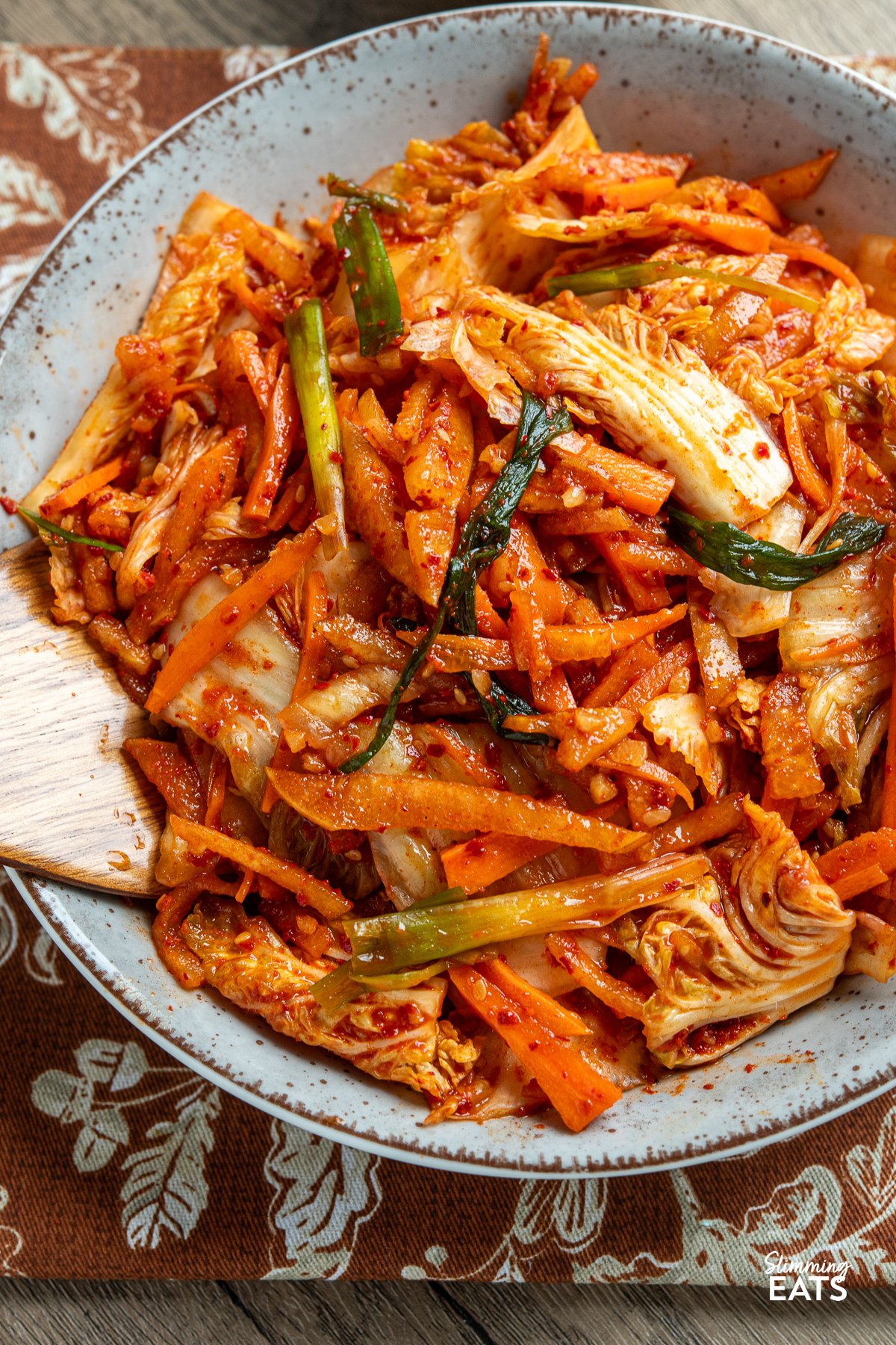 Looking to add a burst of vibrant flavour to your meals without the strong tang of traditional fermented kimchi? This quick and easy fresh kimchi recipe is the perfect introduction. By skipping the fermentation process, you get a crunchy, refreshing side dish that pairs wonderfully with all your favourite Korean dishes. Made with crisp napa cabbage, crunchy carrots, green onions, and sweet Asian pear, this delightful kimchi offers a spicy yet lightly sweet taste that will soon become a staple at your table. quick fresh kimchi freshly prepared in a large bowl with wooden spoon place in kimchi