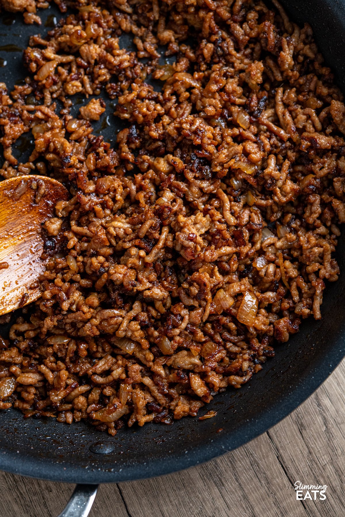 spicy korean gochujang ground pork in a frying pan with wooden spoon