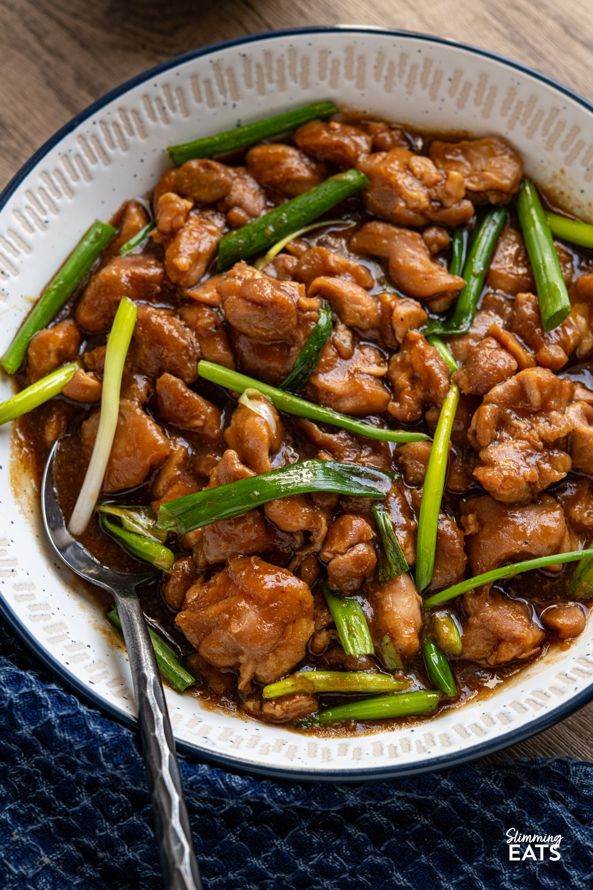Slow Cooker Mongolian Chicken is a fuss-free dinner that’s brimming with bold, savoury-sweet flavours. Tender chicken is coated in a rich, glossy sauce made with soy, garlic, and a touch of brown sugar, creating a melt-in-your-mouth meal the whole family will love. Pair it with fluffy jasmine rice for a comforting dish that tastes like a takeaway classic! close up of slow cooker mongolian chicken in a white bowl with navy blue rim
