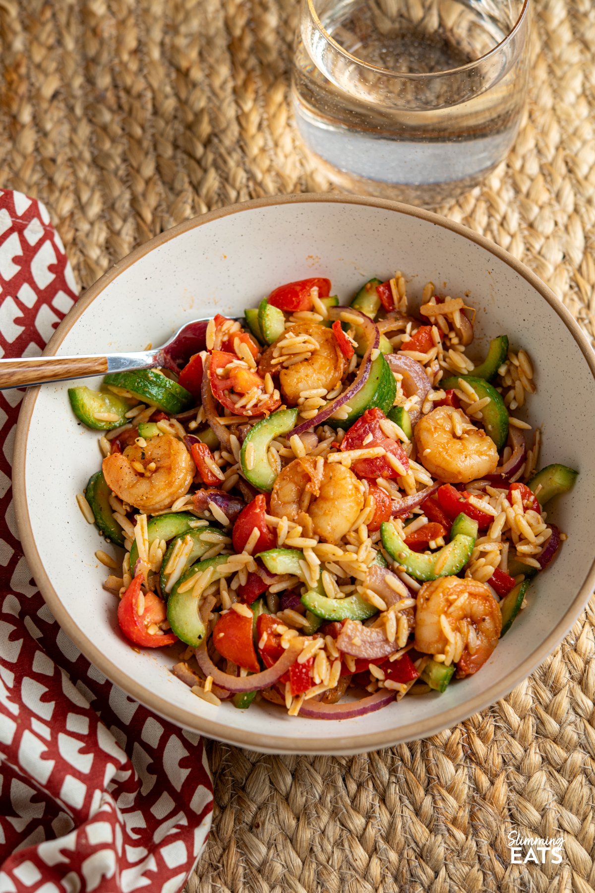 Fresh, vibrant, and packed with flavour—this Shrimp Orzo Salad is a summer stunner. Tender orzo tossed with crisp cucumber, juicy cherry tomatoes, and slivers of red onion forms the perfect base for buttery prawns, pan-fried with garlic, parsley, paprika and a hint of chilli. A drizzle of honey, a squeeze of lime, and a generous grating of Parmesan tie it all together with a sweet-savoury kick. serving of Easy Shrimp Orzo Salad in a white bowl with beige rim.