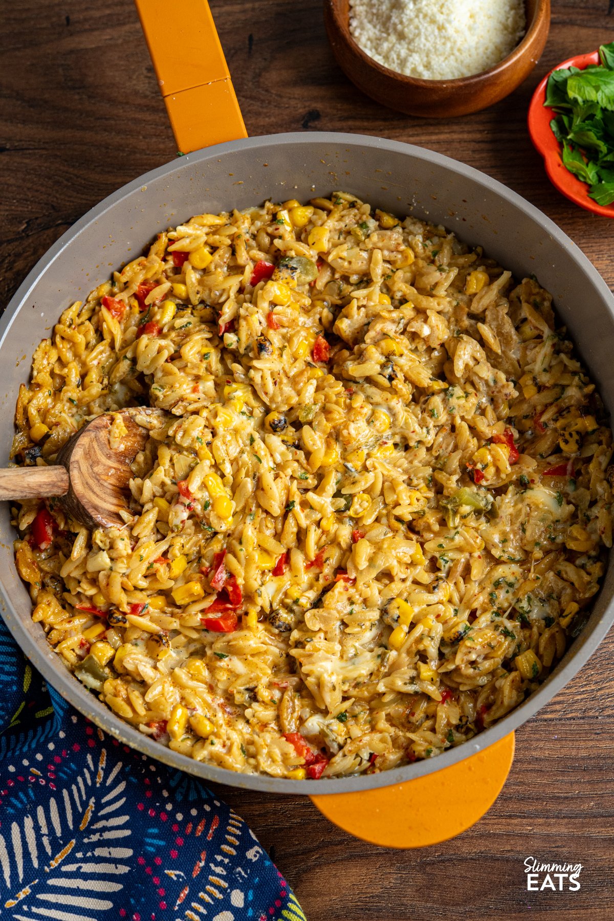 This One Pot Creamy Cheesy Spicy Corn Orzo is the kind of throw-together dinner that tastes like you put in way more effort than you actually did. It starts with smoky charred corn—bringing a hit of sweetness and depth—then builds into a cosy, creamy dish with just enough heat to keep things interesting. Think mac and cheese meets chilli-spiked corn chowder. One Pot Creamy Cheesy Spicy Corn Orzo served in a yellow non-stick skillet, with grated Parmesan in a small wooden bowl on the side.