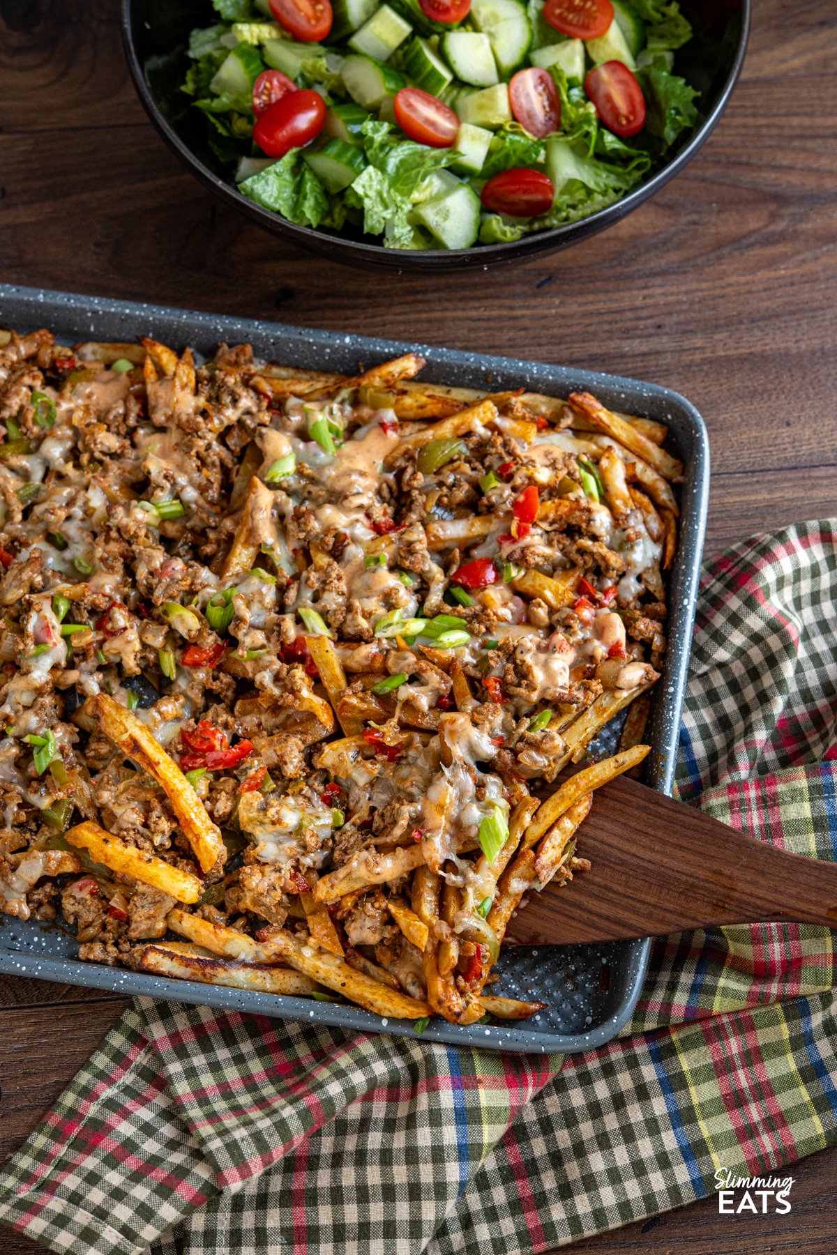Say hello to the filthiest fries you’ll ever fall in love with. These Cajun Dirty Loaded Fries take all the bold, savoury flavour of dirty rice and throw it over a bed of golden homemade fries. A sizzling mix of ground beef and pork is cooked down with peppers and Cajun spices until rich and irresistible, then spooned generously over your chips like it owns the place. cheesy cajun dirty loaded fries on baking sheet with a bowl of mixed salad to the side.