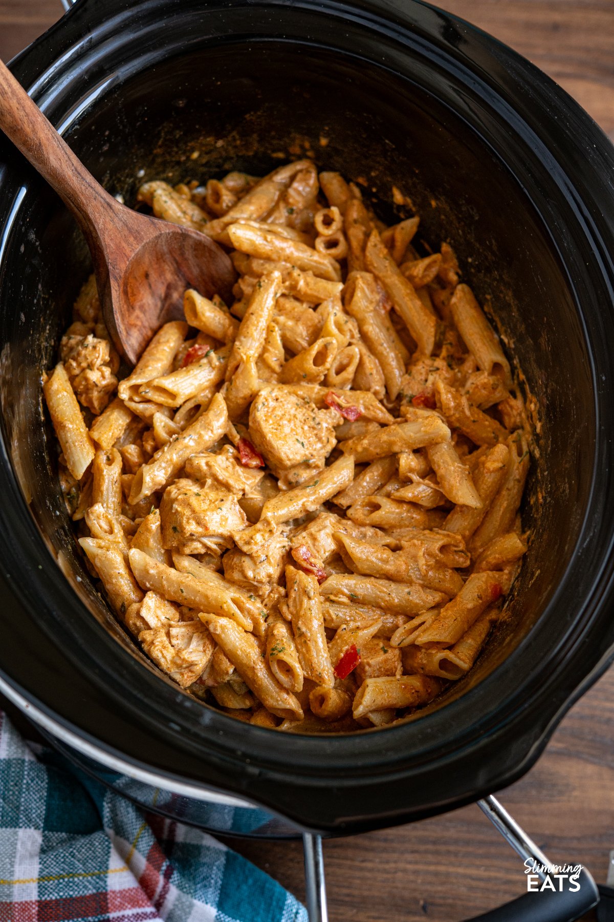Slow Cooker Creamy Cajun Chicken Pasta is an easy, all-in-one meal with tender chicken, a light creamy sauce, and pasta cooked right in the slow cooker. Slow Cooker Creamy Cajun Chicken Pasta in slow cooker with a wooden spoon stirring the pasta