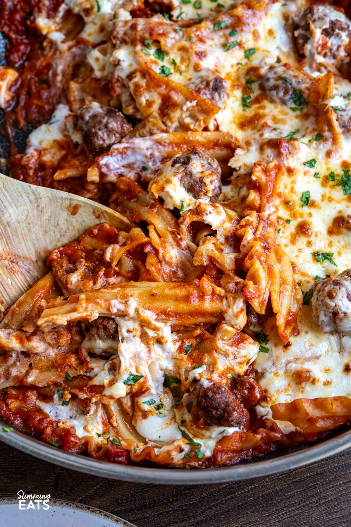 This One Pan Lasagna Meatball Skillet combines tender homemade meatballs, broken lasagne sheets, and a rich tomato sauce with a lighter creamy béchamel for a comforting, fuss free family friendly dinner. close up of One Pan Lasagna Meatballs in double handled non stick skillet