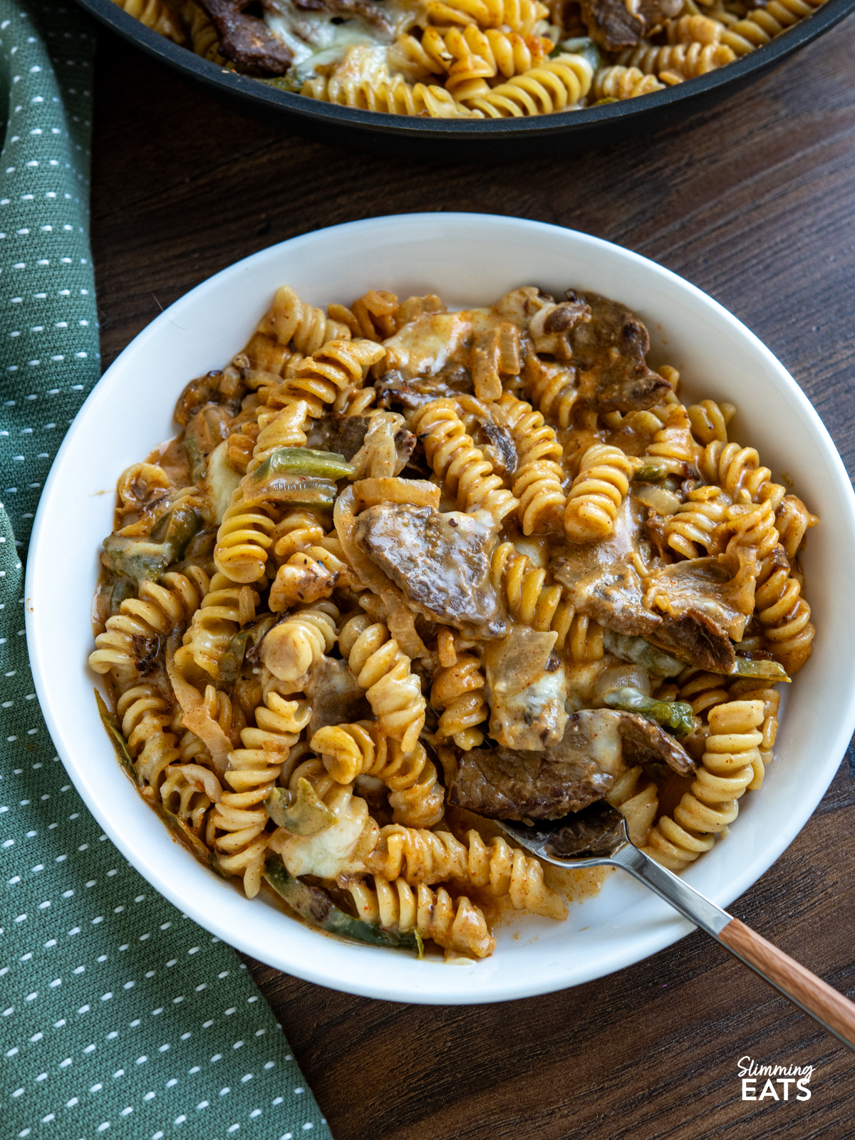 This One Pot Philly Cheesesteak Pasta is a creamy, cheesy twist on the classic sandwich, with tender beef, peppers, and onions all cooked together for an easy, comforting meal. serving of One Pot Philly Cheesesteak Pasta in a small white bowl with fork