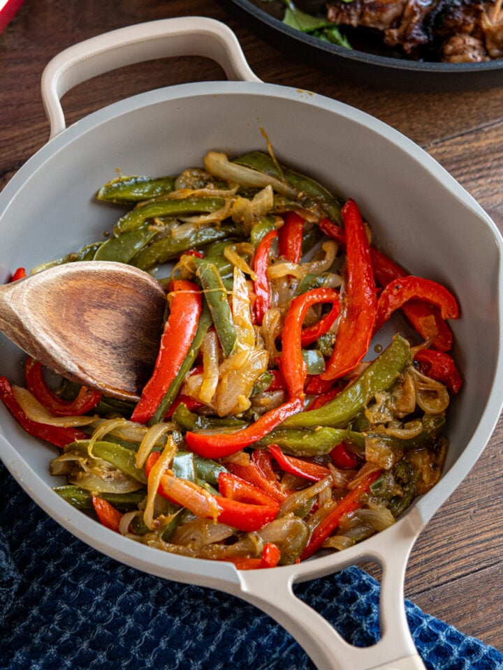 sauteed peppers with onion in non stick pan with wooden spoon