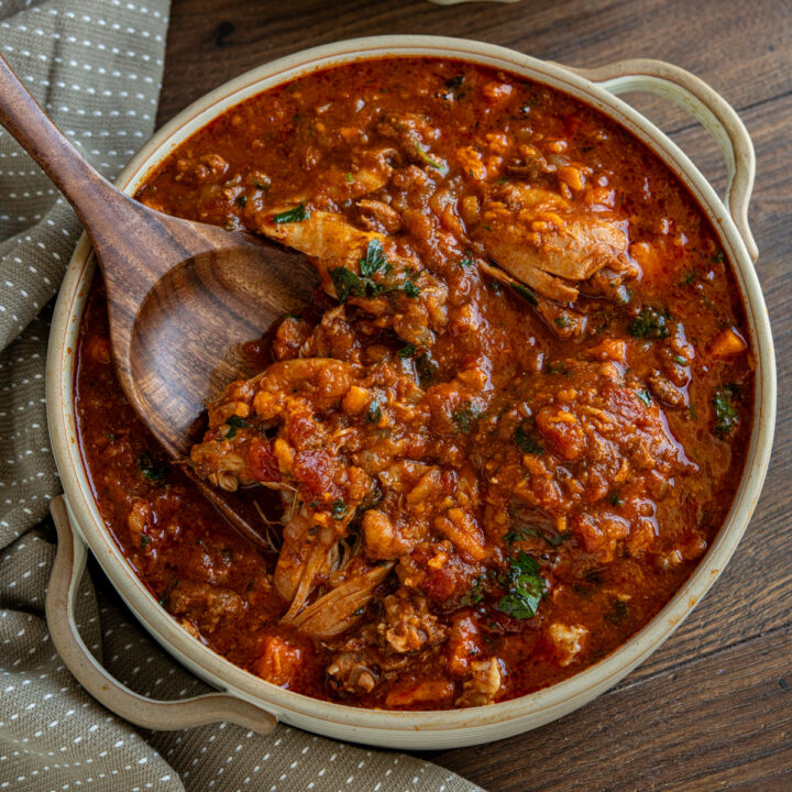 slow cooker chicken chorizo sweet potato stew in ceramic double handled round dish with wooden spoon