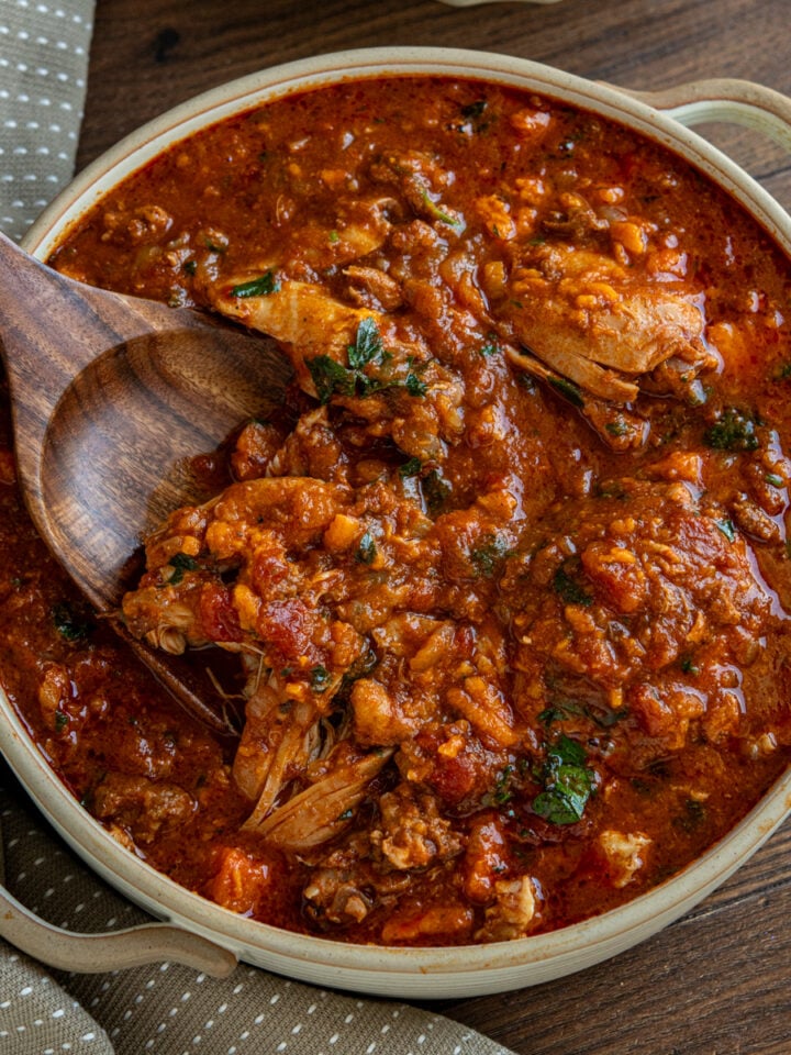 slow cooker chicken chorizo sweet potato stew in ceramic double handled round dish with wooden spoon