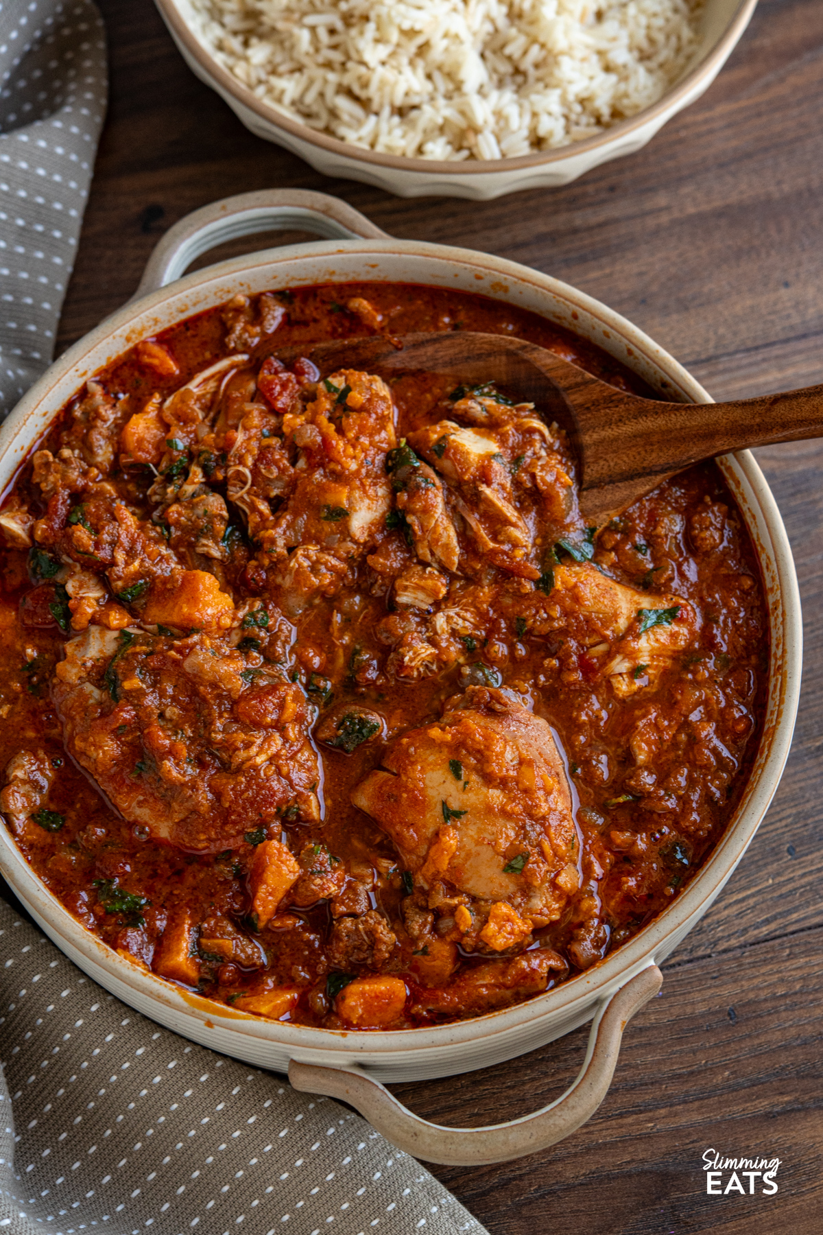 This Slow Cooker Chicken, Chorizo and Sweet Potato Stew is a hearty, flavour-packed meal that brings comfort and richness to any table. Slow Cooker Chicken Chorizo Sweet Potato Stew in double handed ceramic dish with bowl of cooked rice on the side.