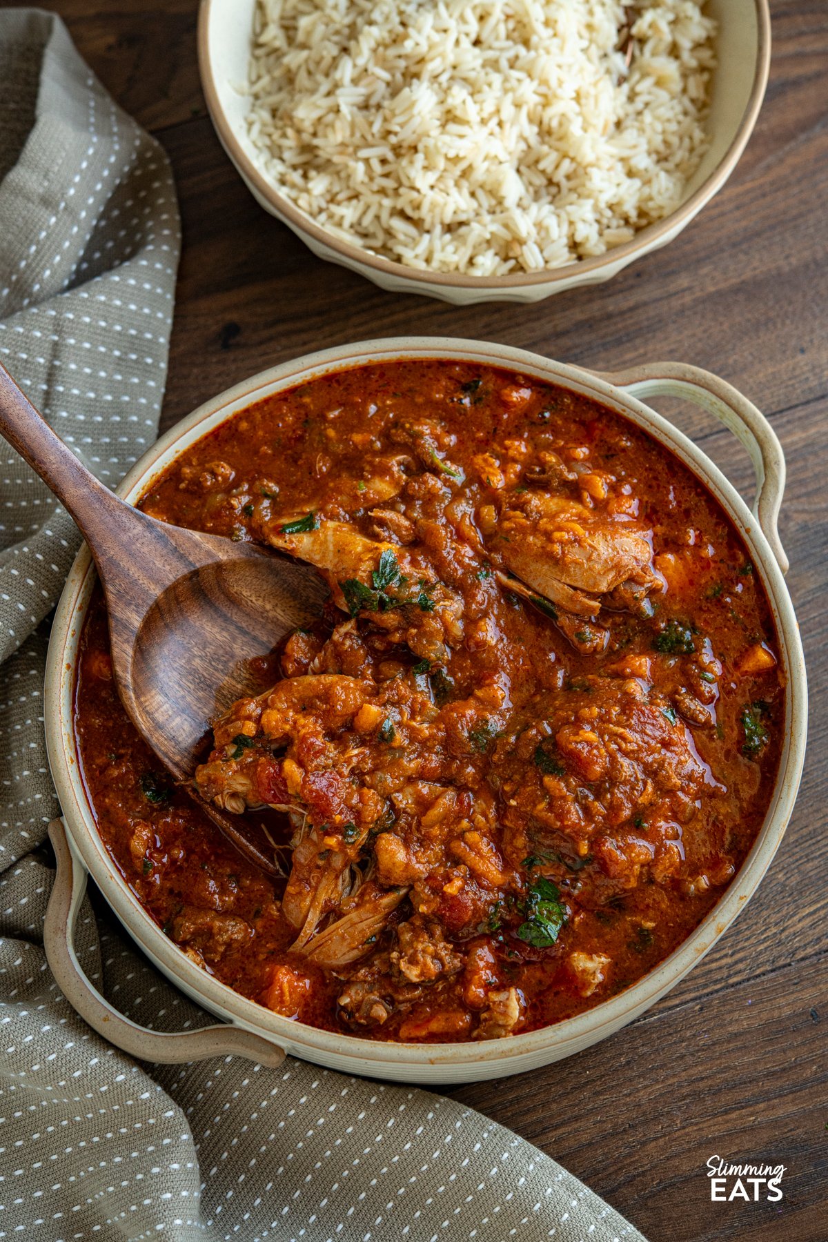 This Slow Cooker Chicken, Chorizo and Sweet Potato Stew is a hearty, flavour-packed meal that brings comfort and richness to any table. Slow Cooker Chicken Chorizo Sweet Potato Stew in double handed ceramic dish with bowl of cooked rice on the side.