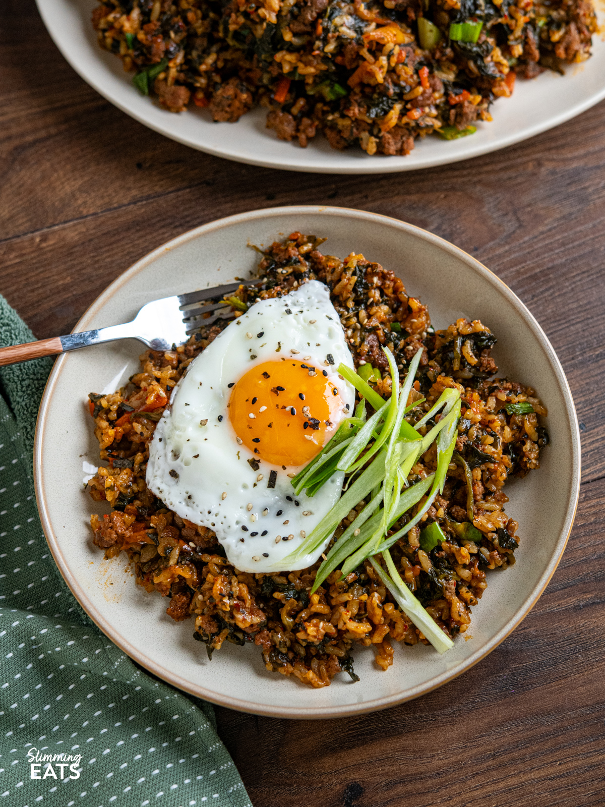 Enjoy the rich, savoury comfort of this Slow Cooker Korean Beef with Spinach and Rice. Ground beef simmers with garlic, ginger, and a sauce where gochujang is the star, alongside spinach and rice for a complete, flavour packed meal. serving of Slow Cooker Korean Beef Spinach Rice in a beige bowl topped with fried egg, sliced green onions, sesame seed nori seasoning