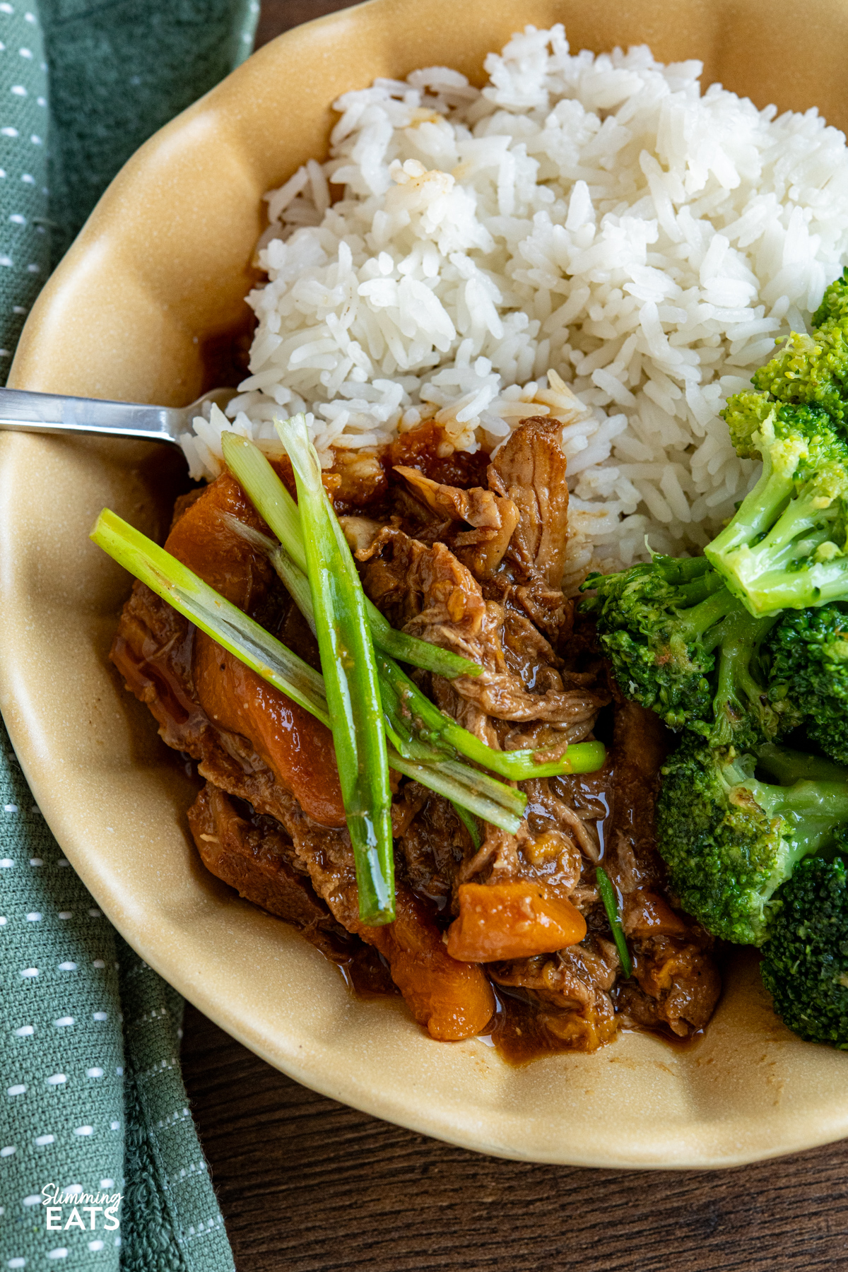 Slow cooker ginger peach pork is the definition of an easy, no fuss meal. You toss a few ingredients into the slow cooker, get on with your day and come back to a family dinner that is warm, comforting and wonderfully simple. cooked Slow Cooker Ginger Peach Pork in a yellow bowl served with rice and steamed broccoli