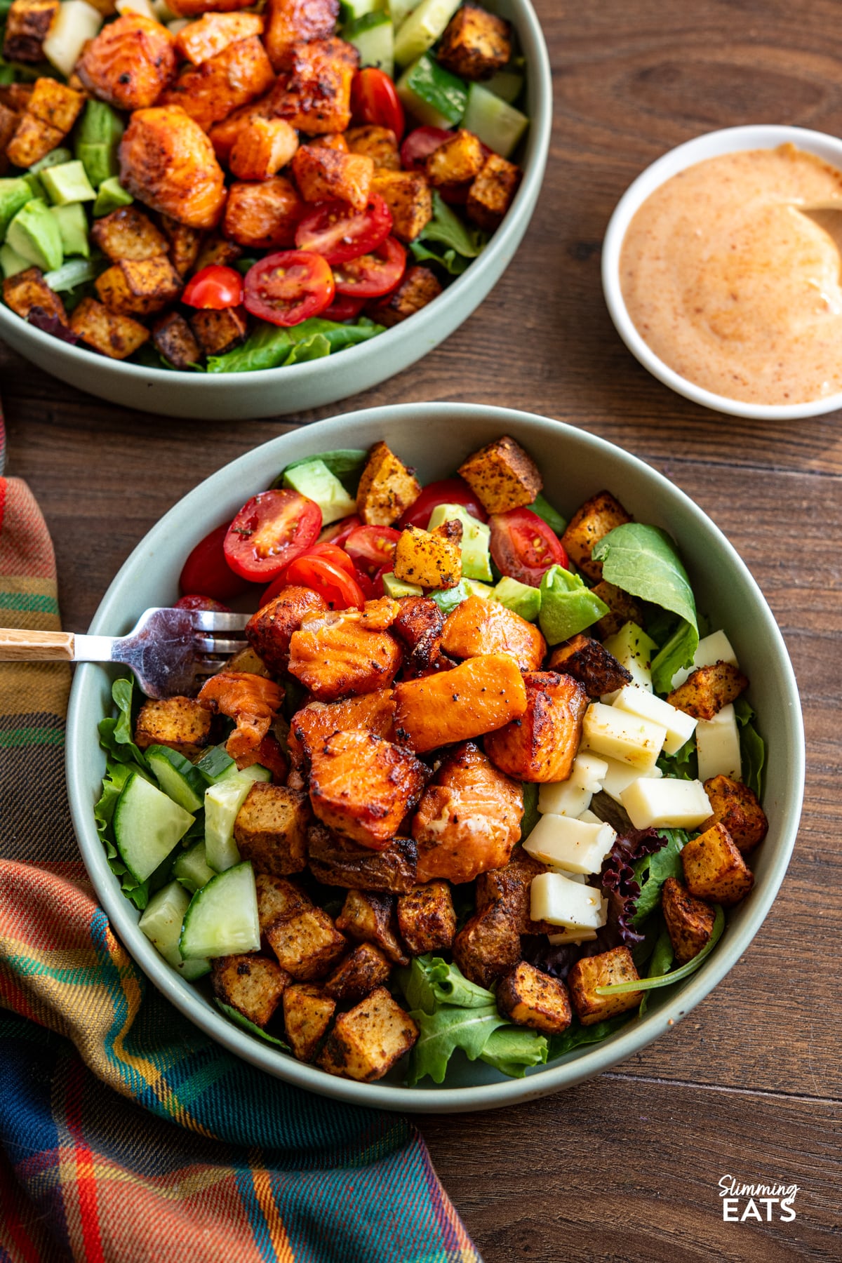 Two Air Fryer Hot Honey Salmon Bowls  featuring salmon, potato, salad, avocado and gouda with dressing on side