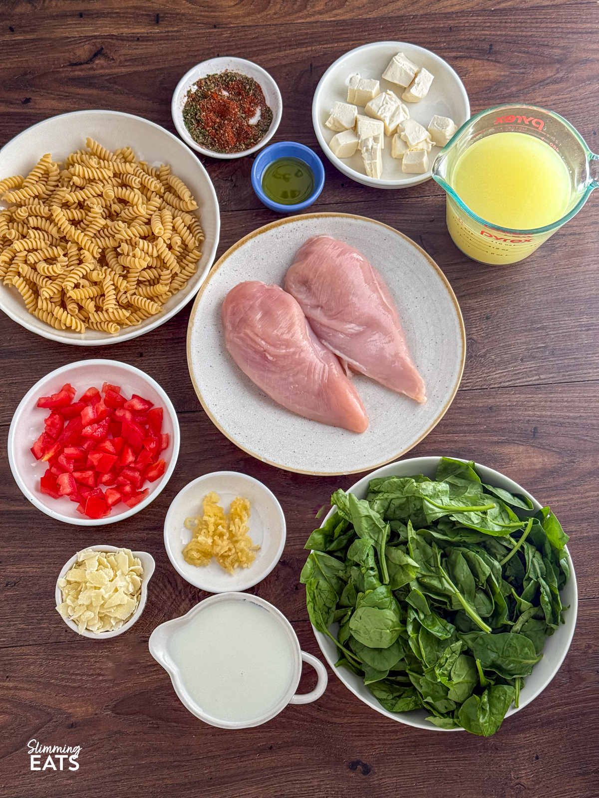 This Slow Cooker Creamy Garlic Chicken Spinach Pasta is an effortless, all-in-one slow cooker meal that’s rich, comforting, and perfect for busy weeknights. a board with all the ingredients shown for slow cooker creamy garlic chicken pasta