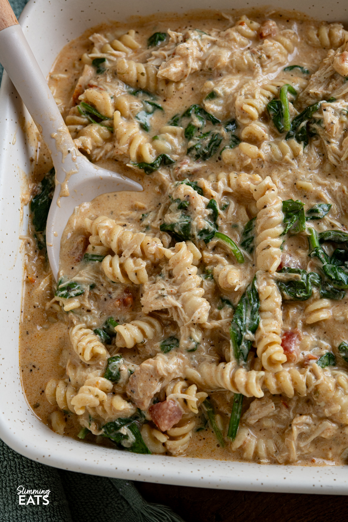 This Slow Cooker Creamy Garlic Chicken Spinach Pasta is an effortless, all-in-one slow cooker meal that’s rich, comforting, and perfect for busy weeknights. close up of Slow Cooker Creamy Garlic Chicken Spinach Pasta in oven dish
