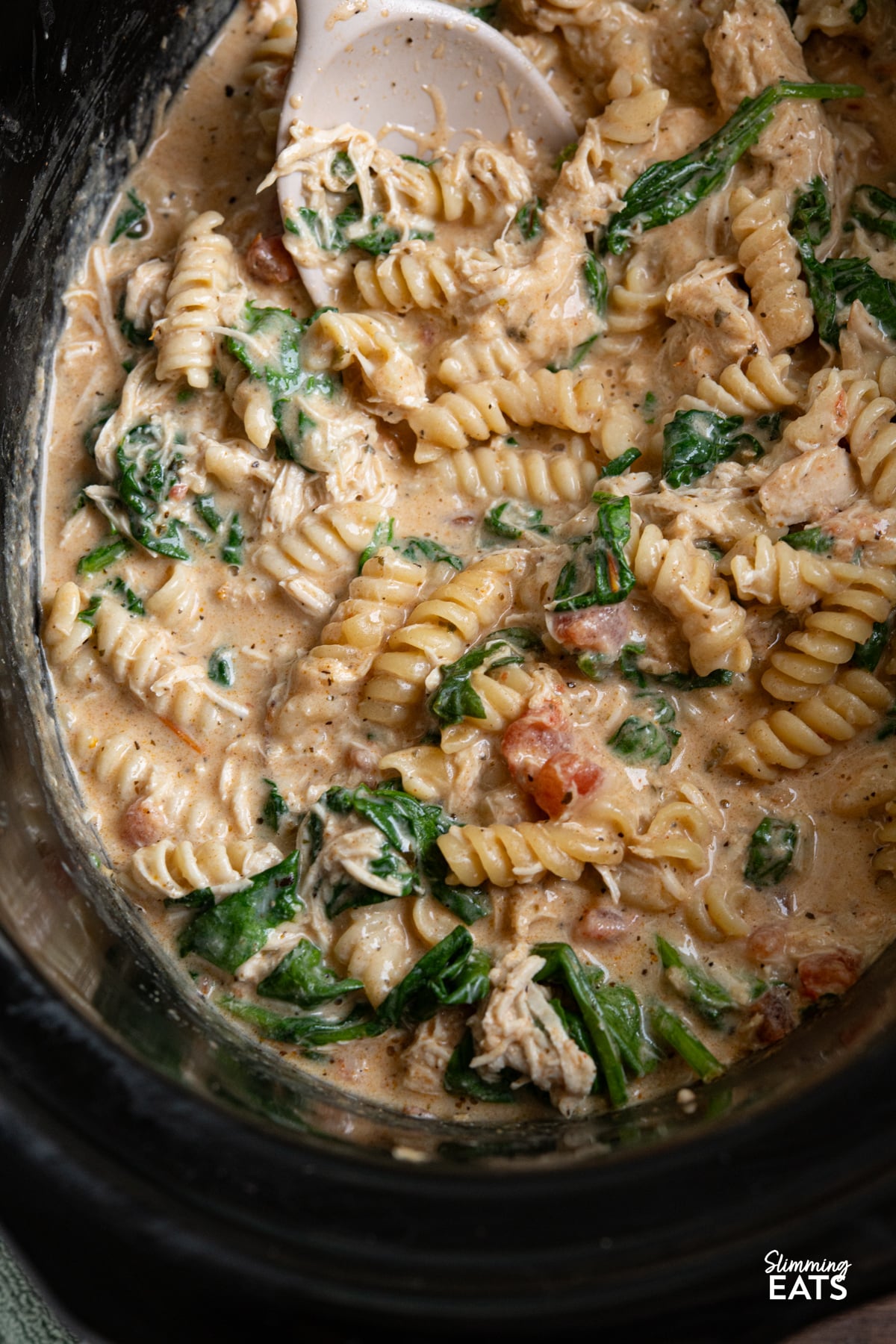 This Slow Cooker Creamy Garlic Chicken Spinach Pasta is an effortless, all-in-one slow cooker meal that’s rich, comforting, and perfect for busy weeknights. Creamy Garlic Chicken Spinach Pasta in slow cooker with spatula