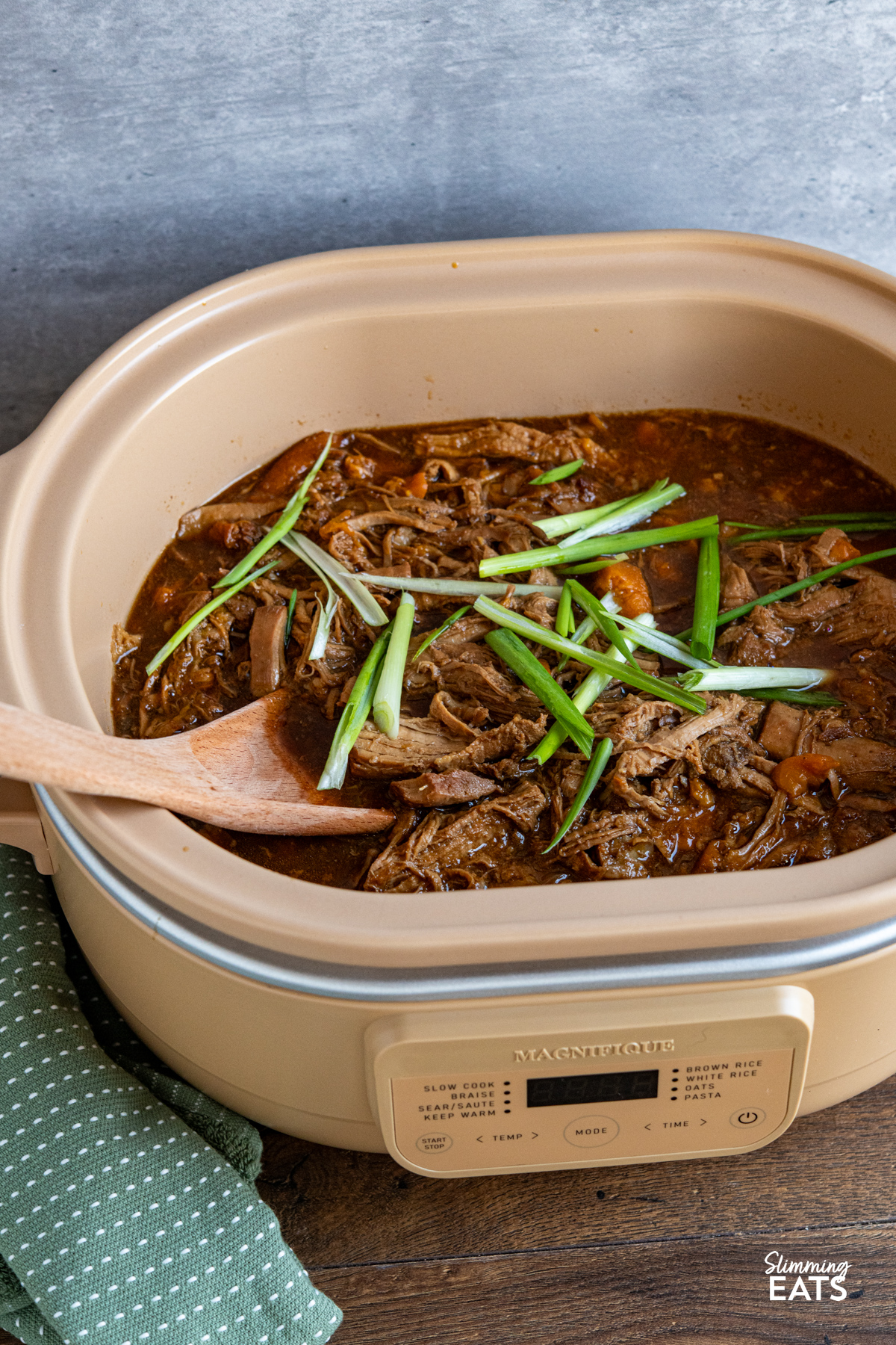 Slow Cooker Ginger Peach Pork cooked in magnique claypot cooker with wooden spoon place in pot