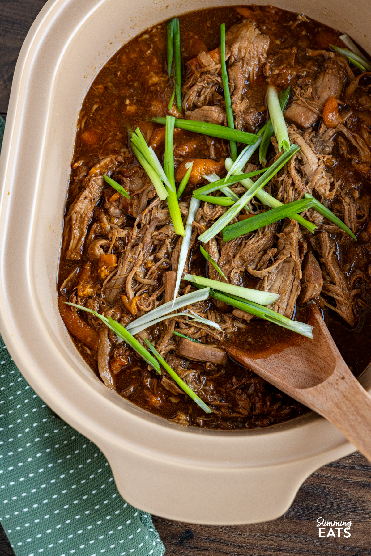 close up of Slow Cooker Ginger Peach Pork cooked in magnique claypot cooker with wooden spoon place in pot