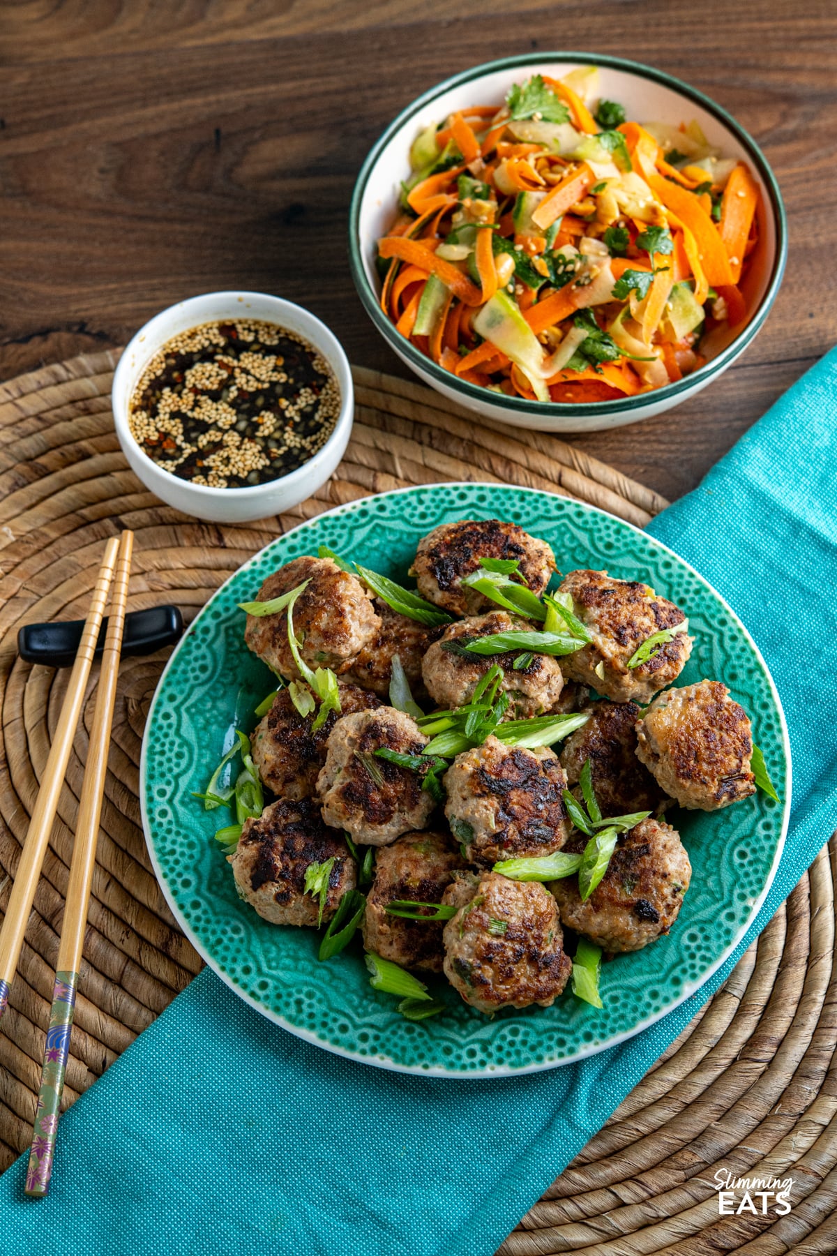 These juicy Asian Chicken Patties are packed with savoury flavour and served with a simple dipping sauce and fresh crunchy salad for an easy, delicious meal. Asian Chicken Patties with Dipping Sauce on jade coloured plate, chopsticks to the left and small white dipping bowl above and carrot, cucumber salad.
