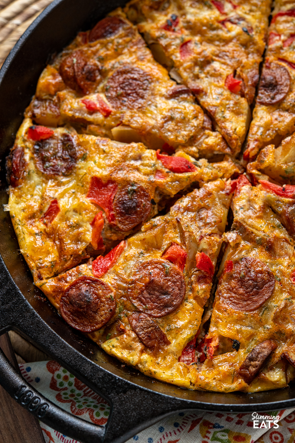 Spicy smoked sausage, tender potato, roasted red pepper and cheddar come together in this easy frittata that is perfect for brunch, lunch or a simple dinner. close up of Spicy Smoked Sausage and Potato Frittata sliced in a black cast iron skillet