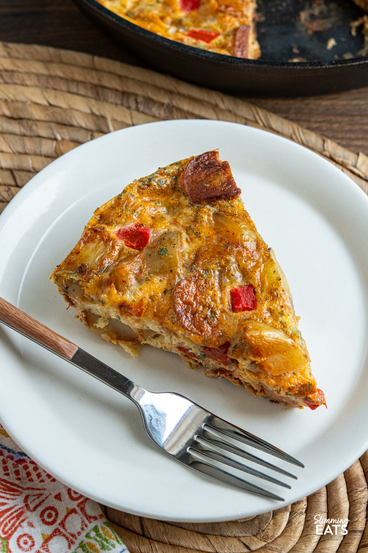 Spicy smoked sausage, tender potato, roasted red pepper and cheddar come together in this easy frittata that is perfect for brunch, lunch or a simple dinner. close up of Spicy Smoked Sausage and Potato Frittata on plate with fork