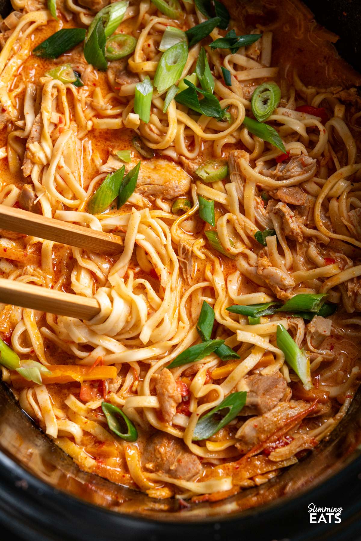 close up of Slow Cooker Coconut Gochujang Chicken Noodles in the crockpot with some chopsticks picking up noodles