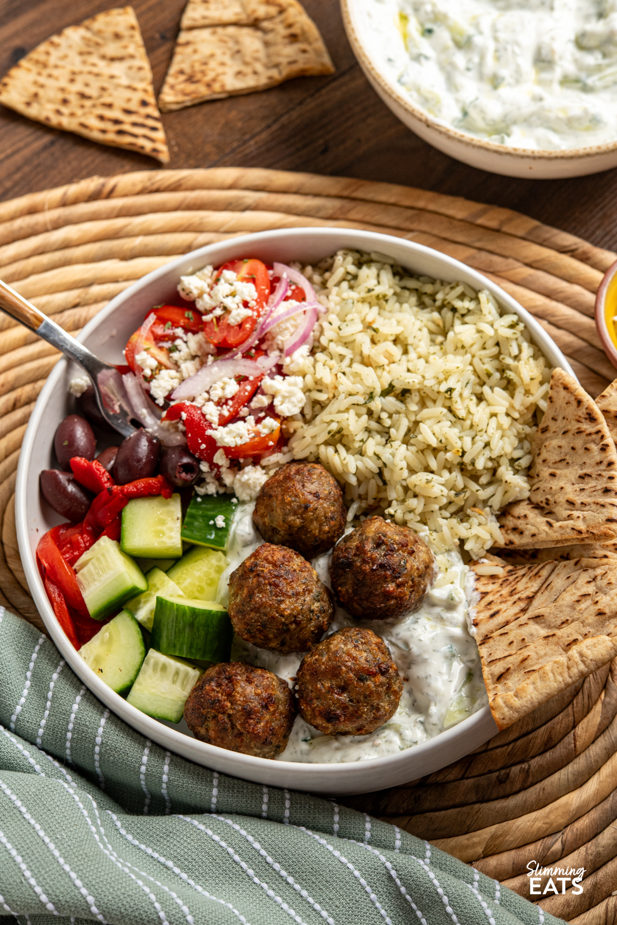 Greek Turkey Meatball Bowls with herby rice, salad, tzatziki, feta, olives and warmed pitta bread, bowl of tzatziki on side. 