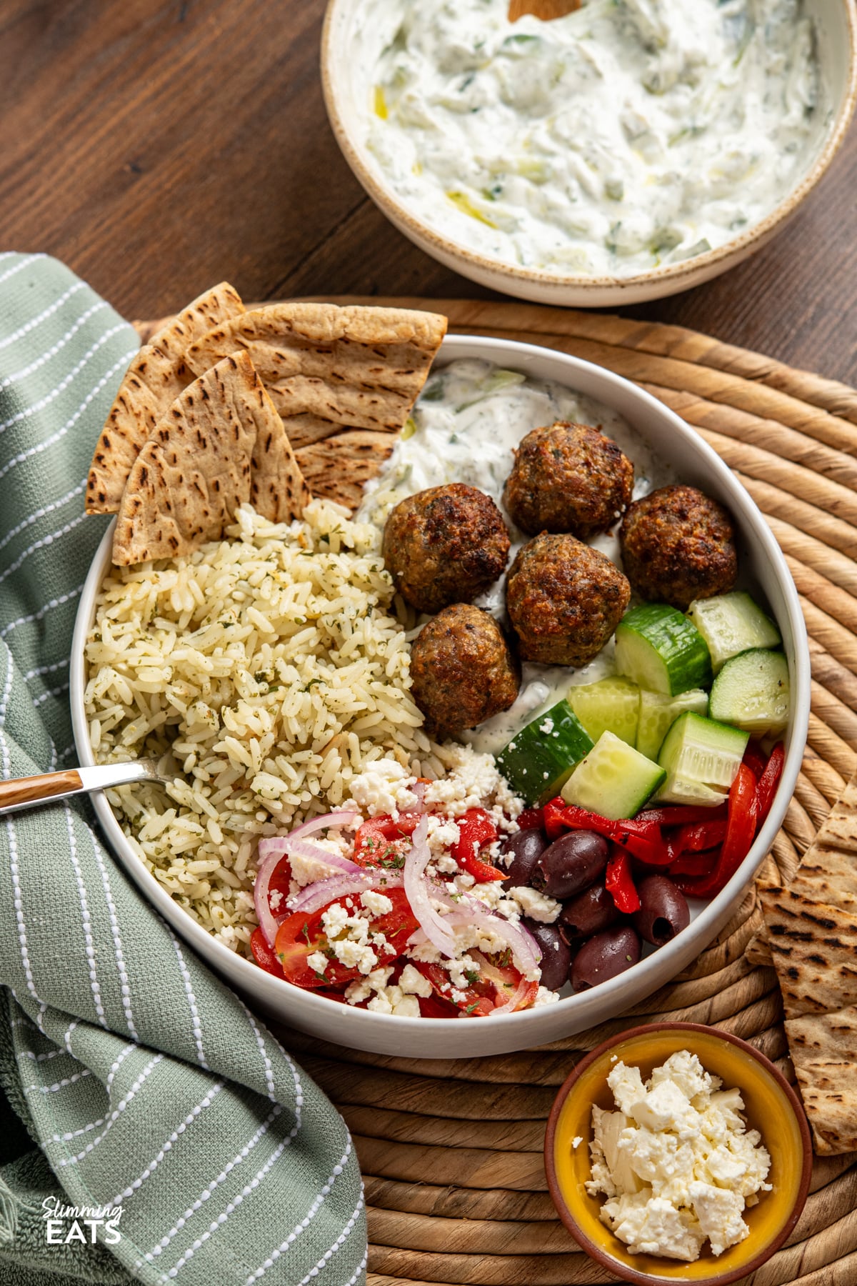 Greek Turkey Meatball Bowls with herby rice, salad, tzatziki, feta, olives and warmed pitta bread, bowl of tzatziki on side. 