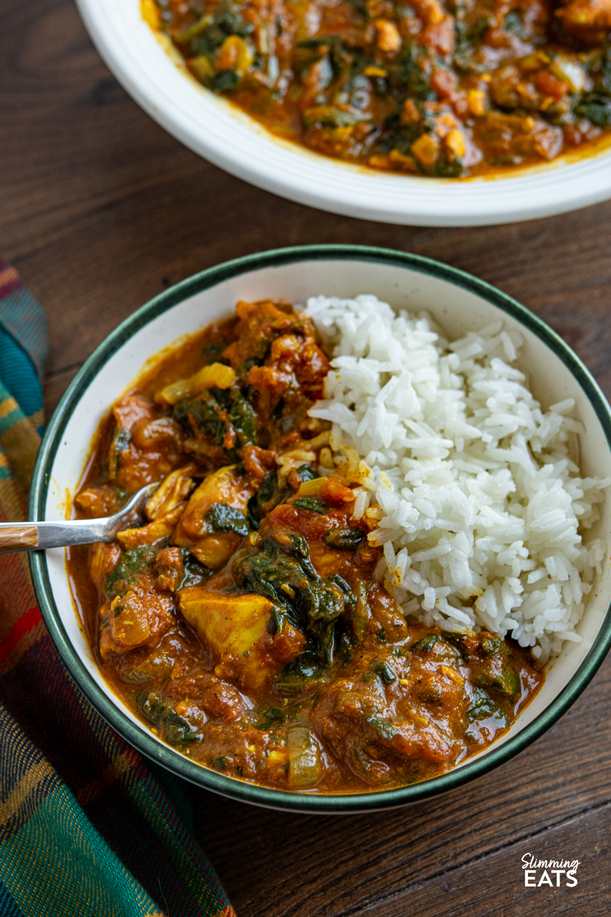 serving of Slow Cooker Easy Chicken Spinach Curry in a white bowl with a green rim