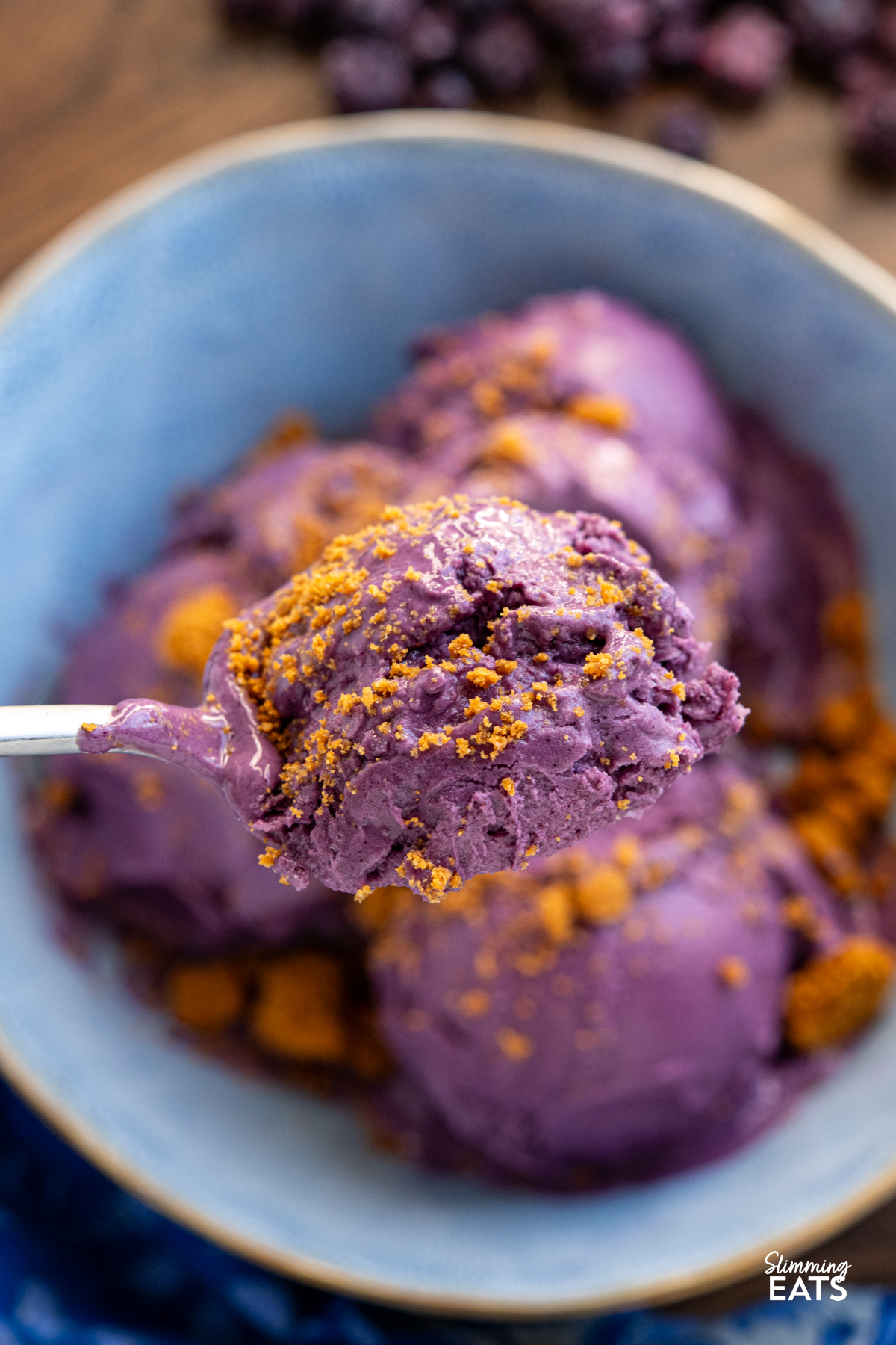 some Blueberry Banana Frozen Yoghurt from a blue bowl being scooped up with a spoon